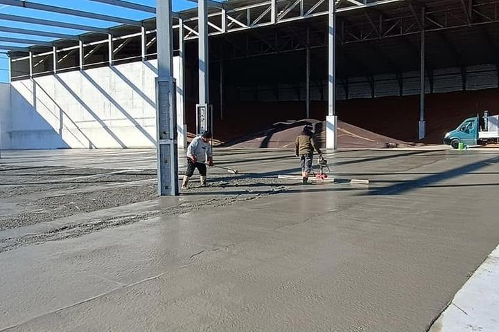 Echipă turnând și nivelând beton într-o hală