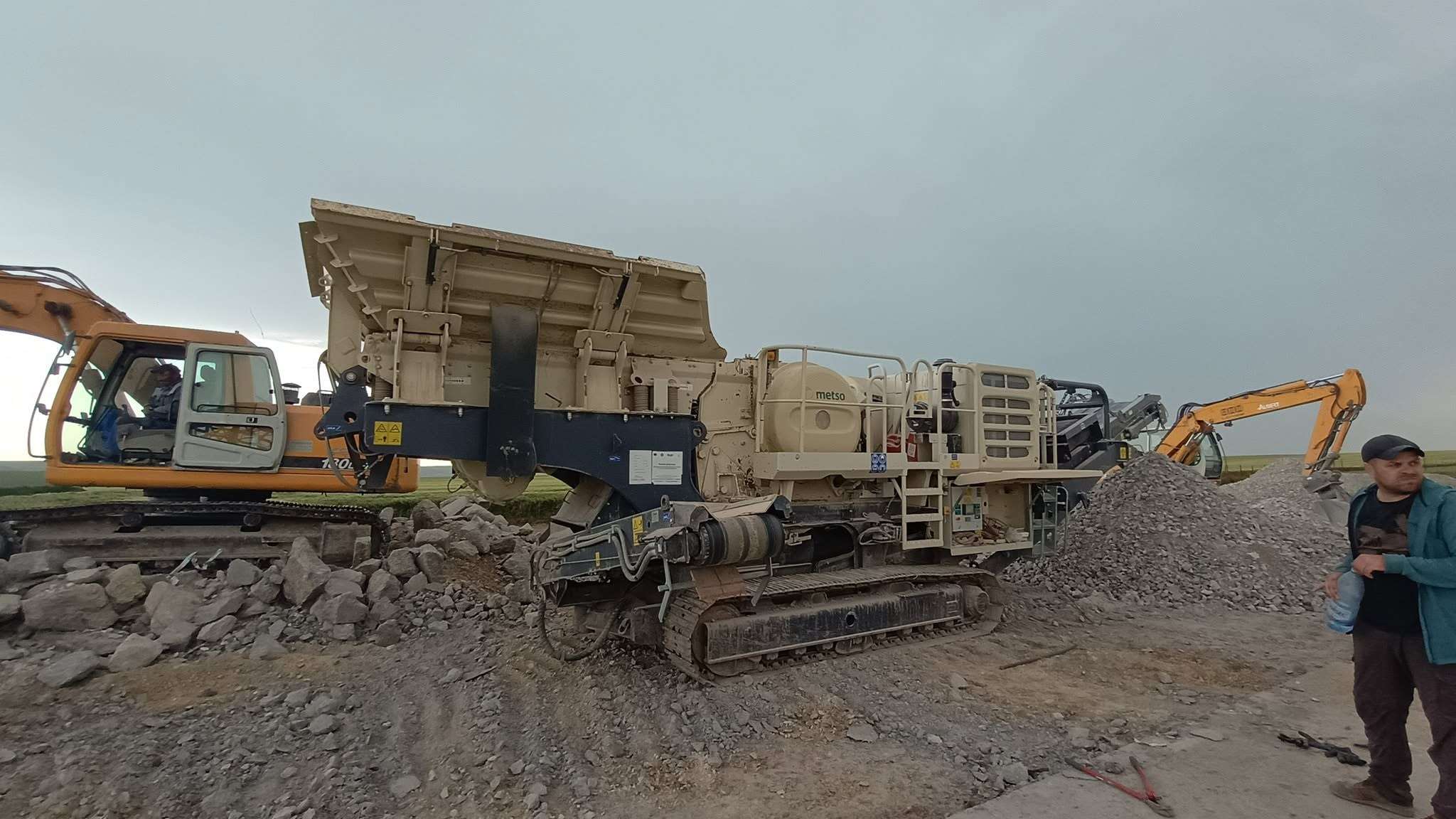 Excavator alimentând concasorul mobil cu beton