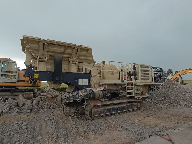Excavator alimentând concasorul mobil cu beton