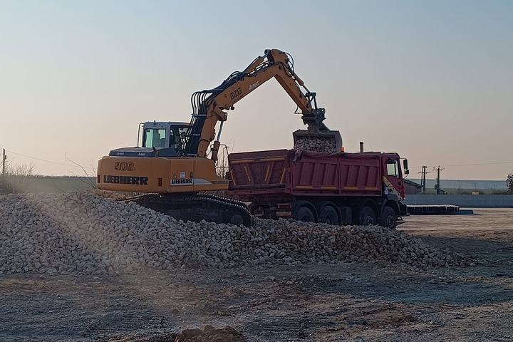 Excavator încărcând o autobasculantă la apus