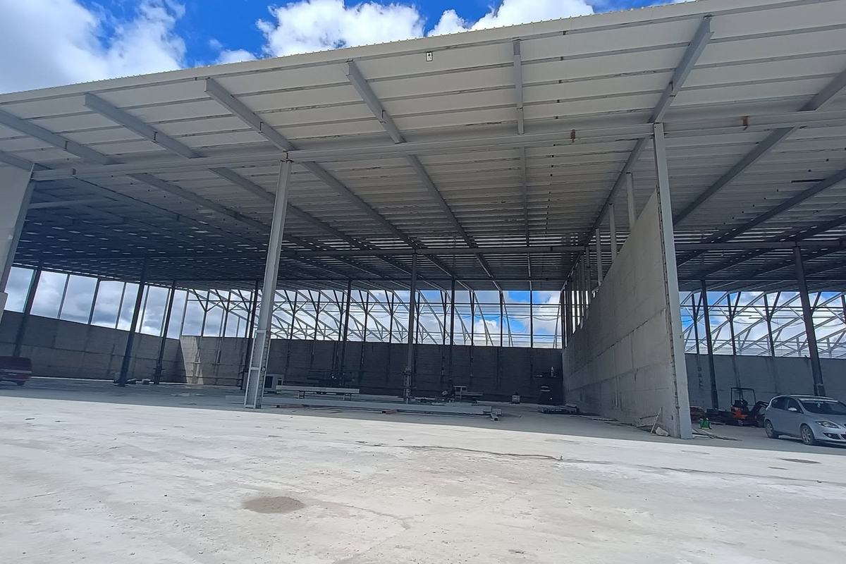Interiorul unei hale mari, deschise, cu pardoseală din beton