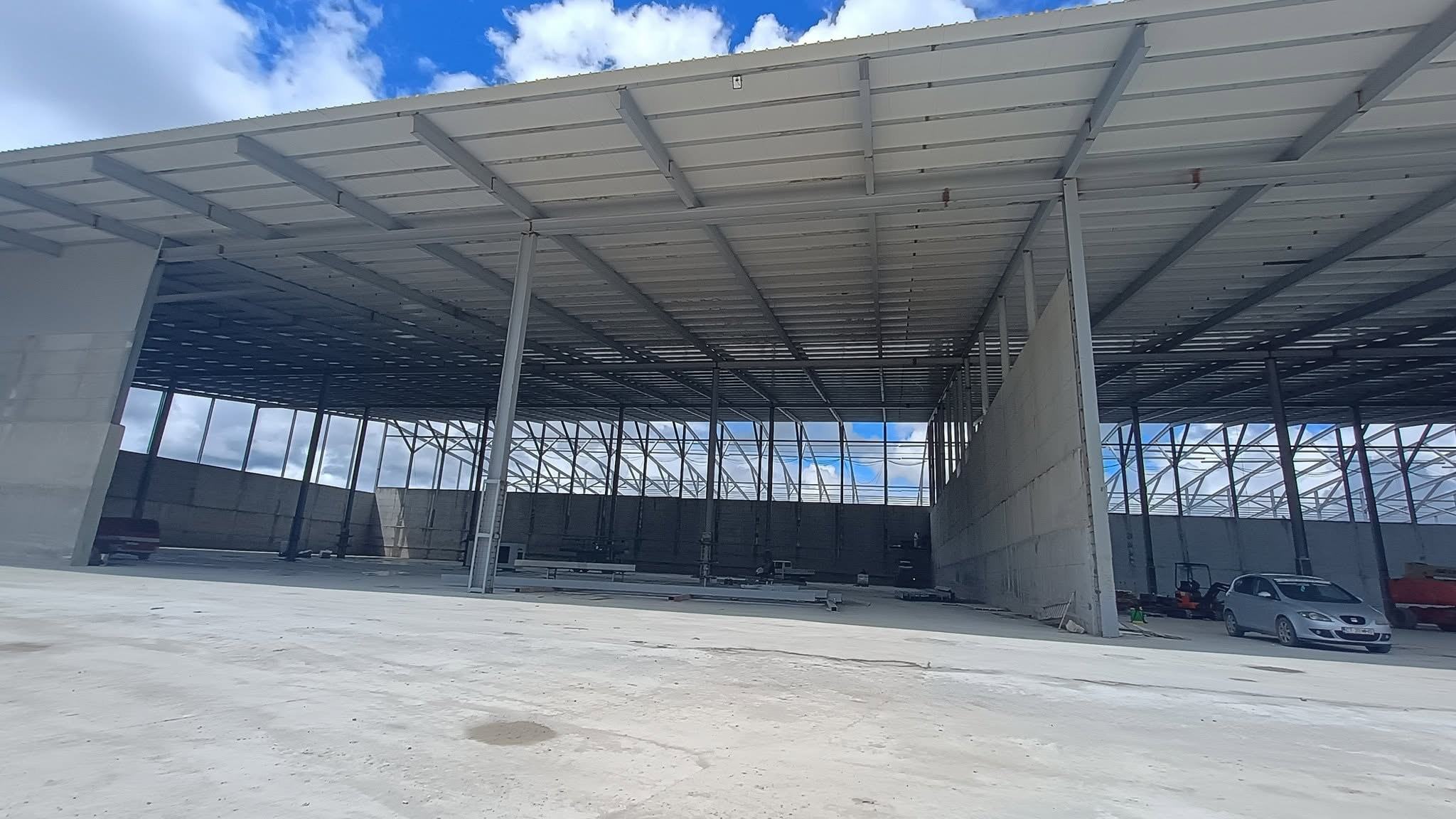 Interiorul unei hale mari, deschise, cu pardoseală din beton