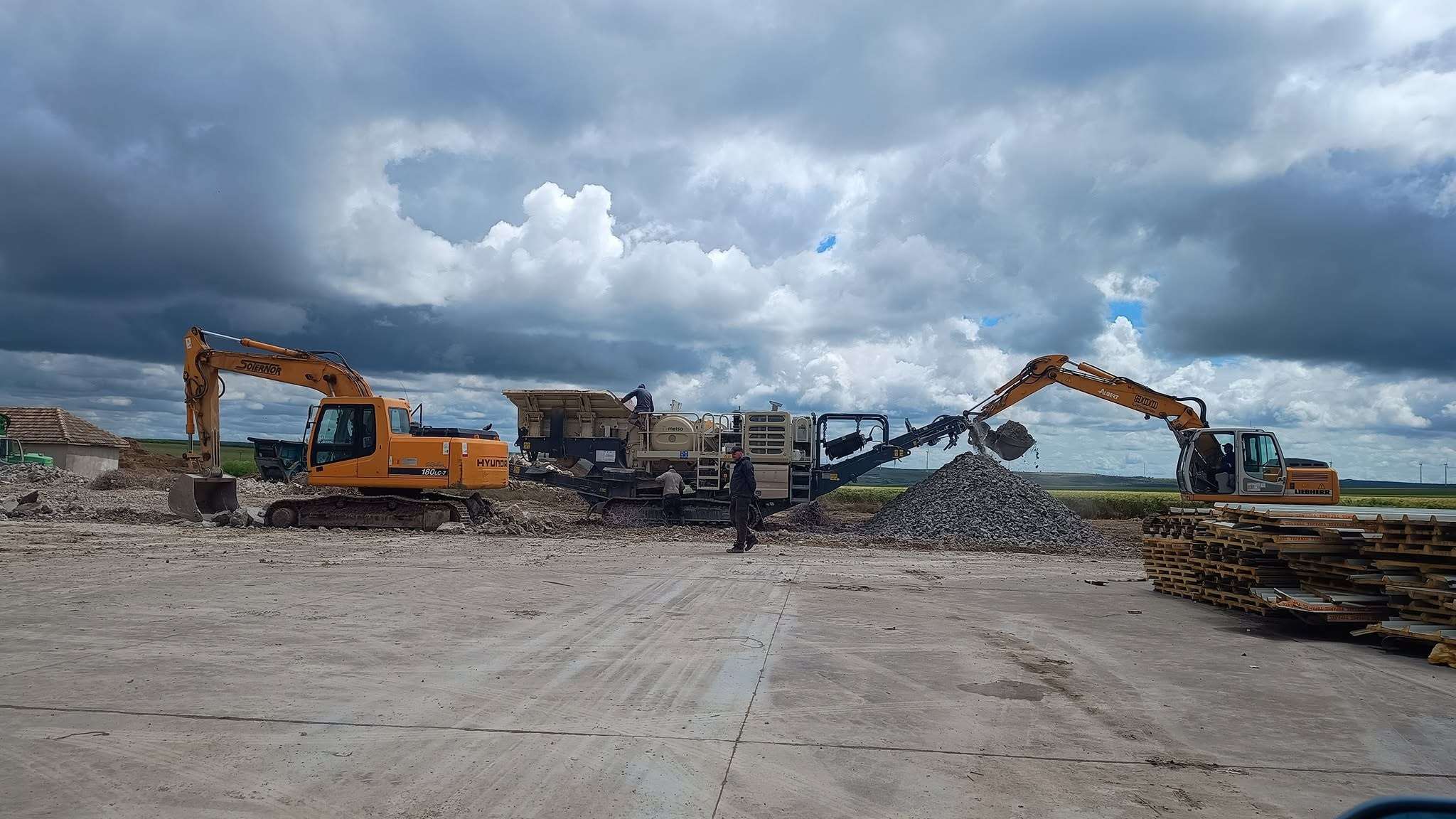 Concasor mobil și două excavatoare la reciclarea betonului pe șantier