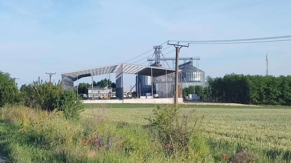 Silozuri metalice pentru cereale, într-un lan de grâu