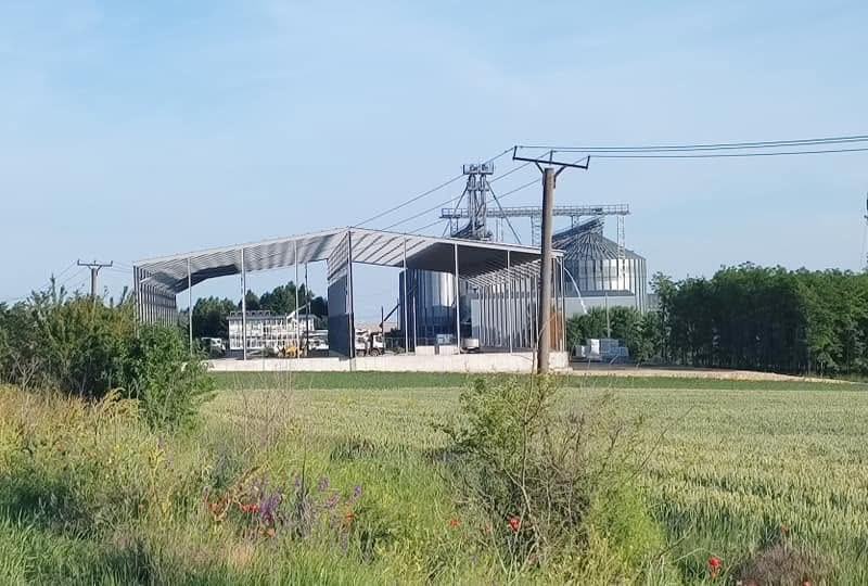 Silozuri metalice pentru cereale, într-un lan de grâu