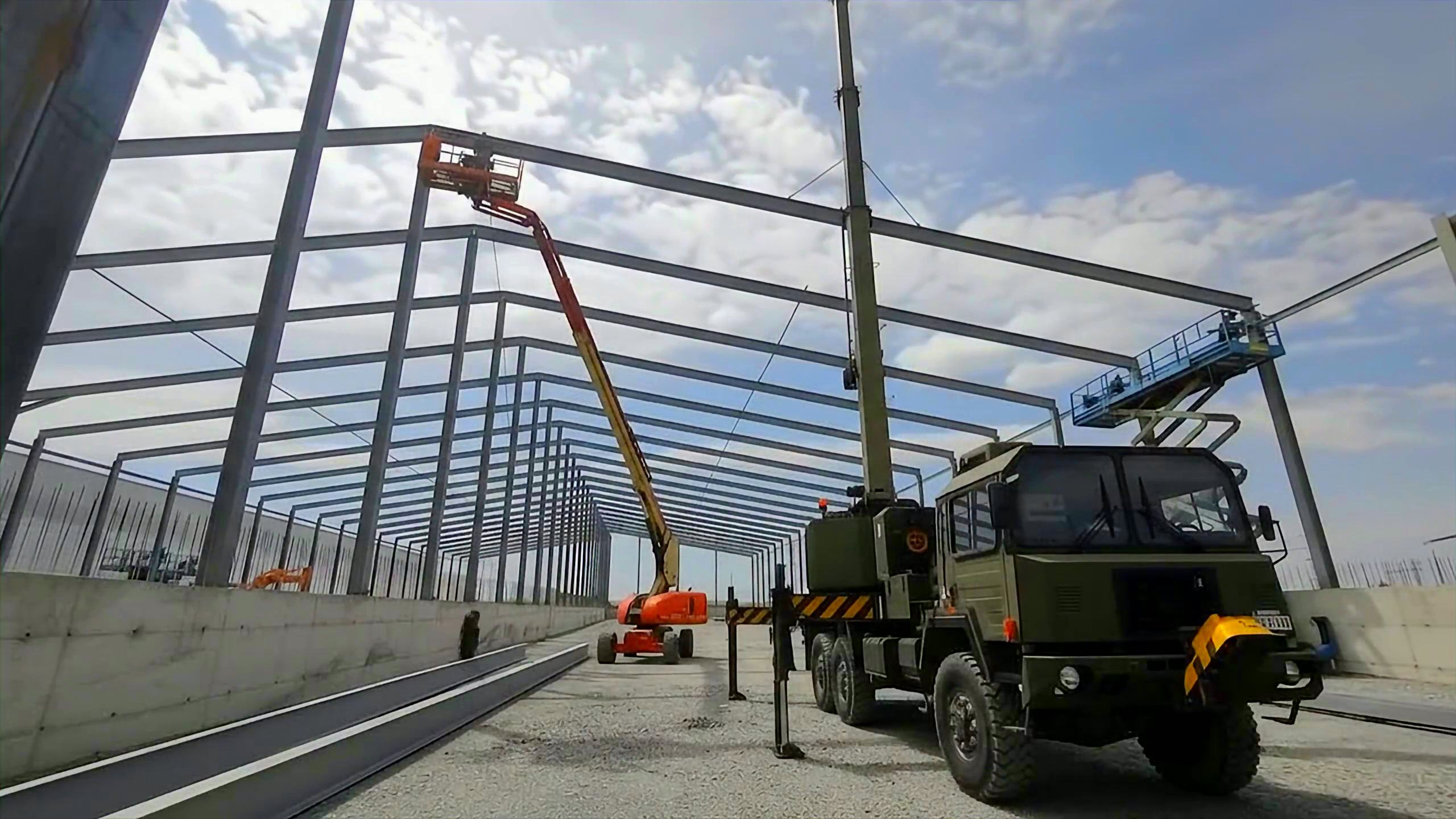 Cadrele portal ale unei hale metalice în montaj, în perspectivă, cu pereți din beton prefabricat