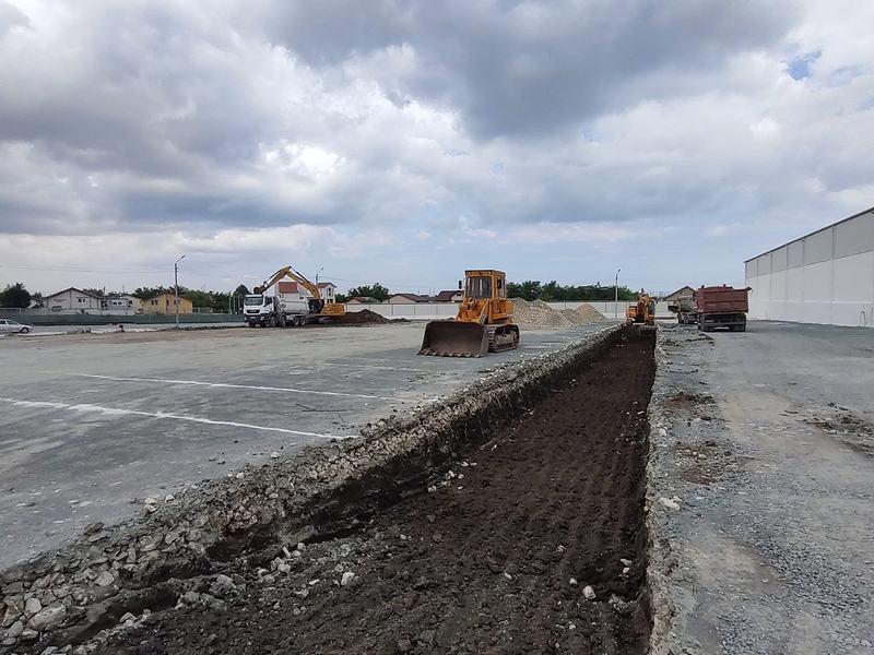 Buldozer nivelând o platformă de pământ lângă o hală