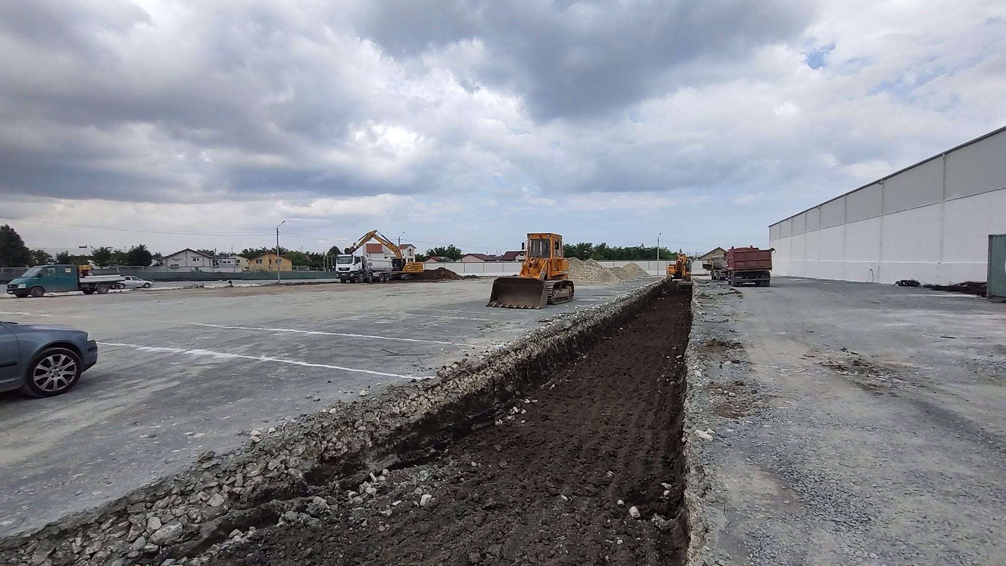 Buldozer nivelând o platformă de pământ lângă o hală