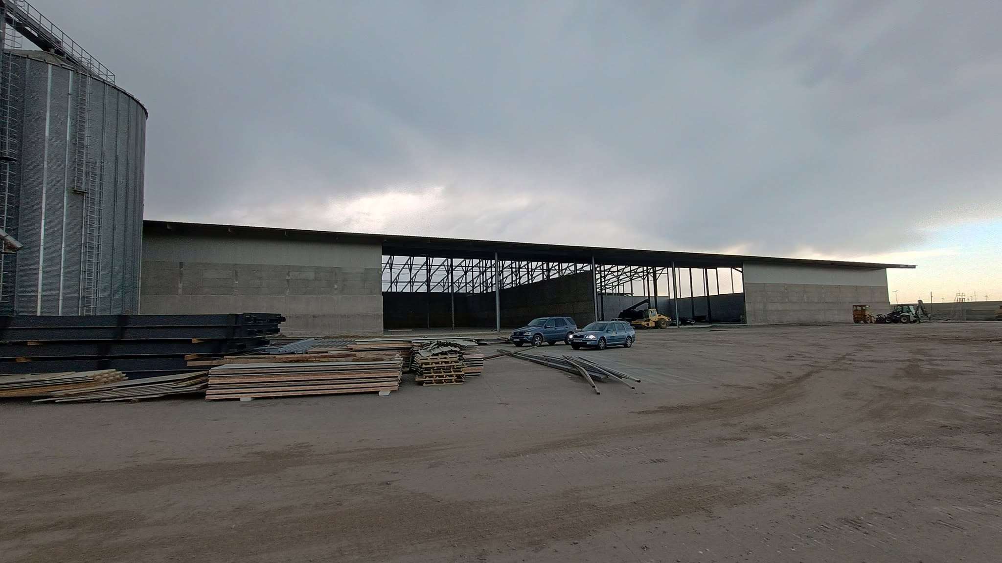 Siloz metalic și hală în construcție pe un șantier agricol