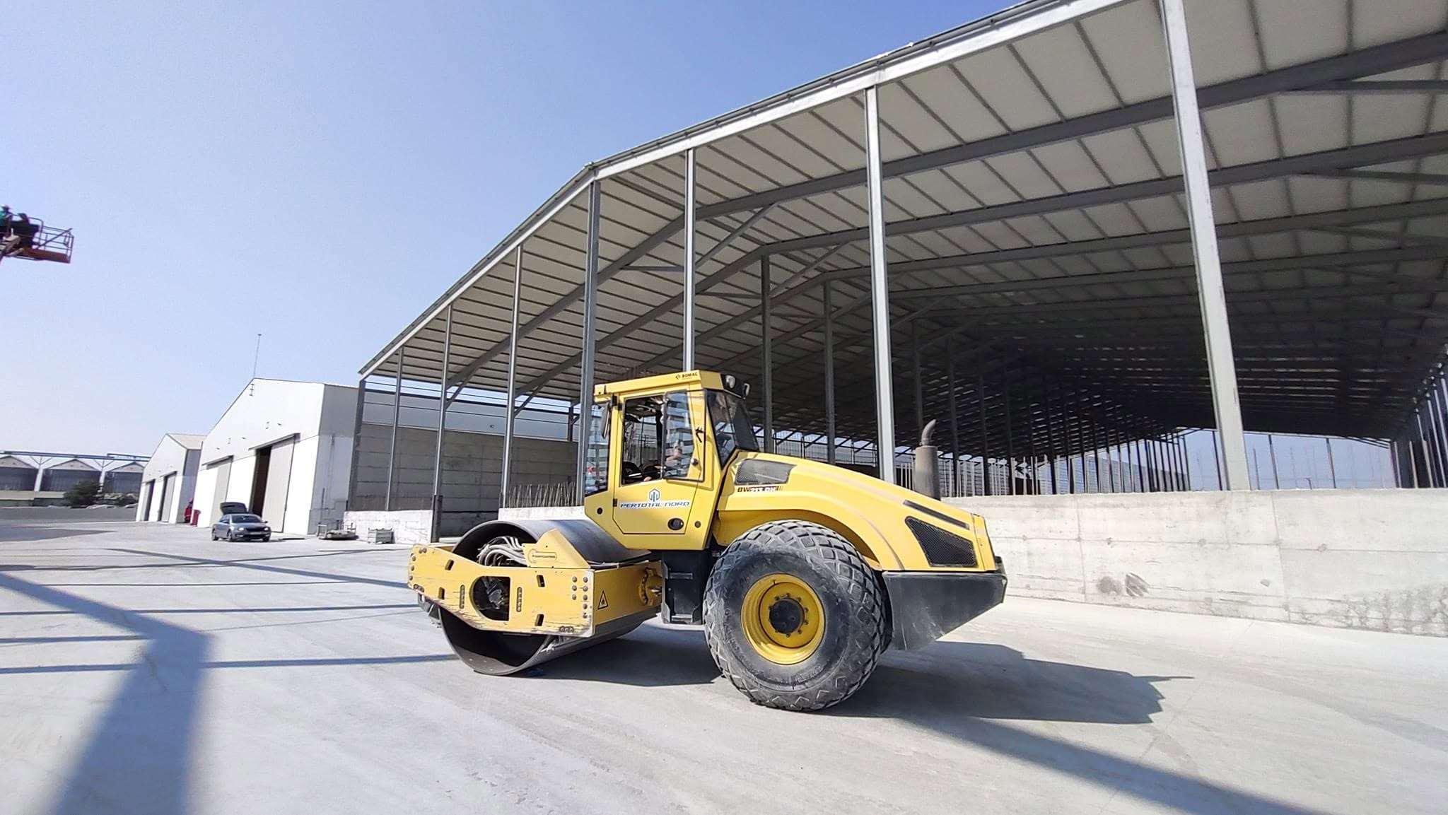 Cilindru compactor galben, pe platformă betonată