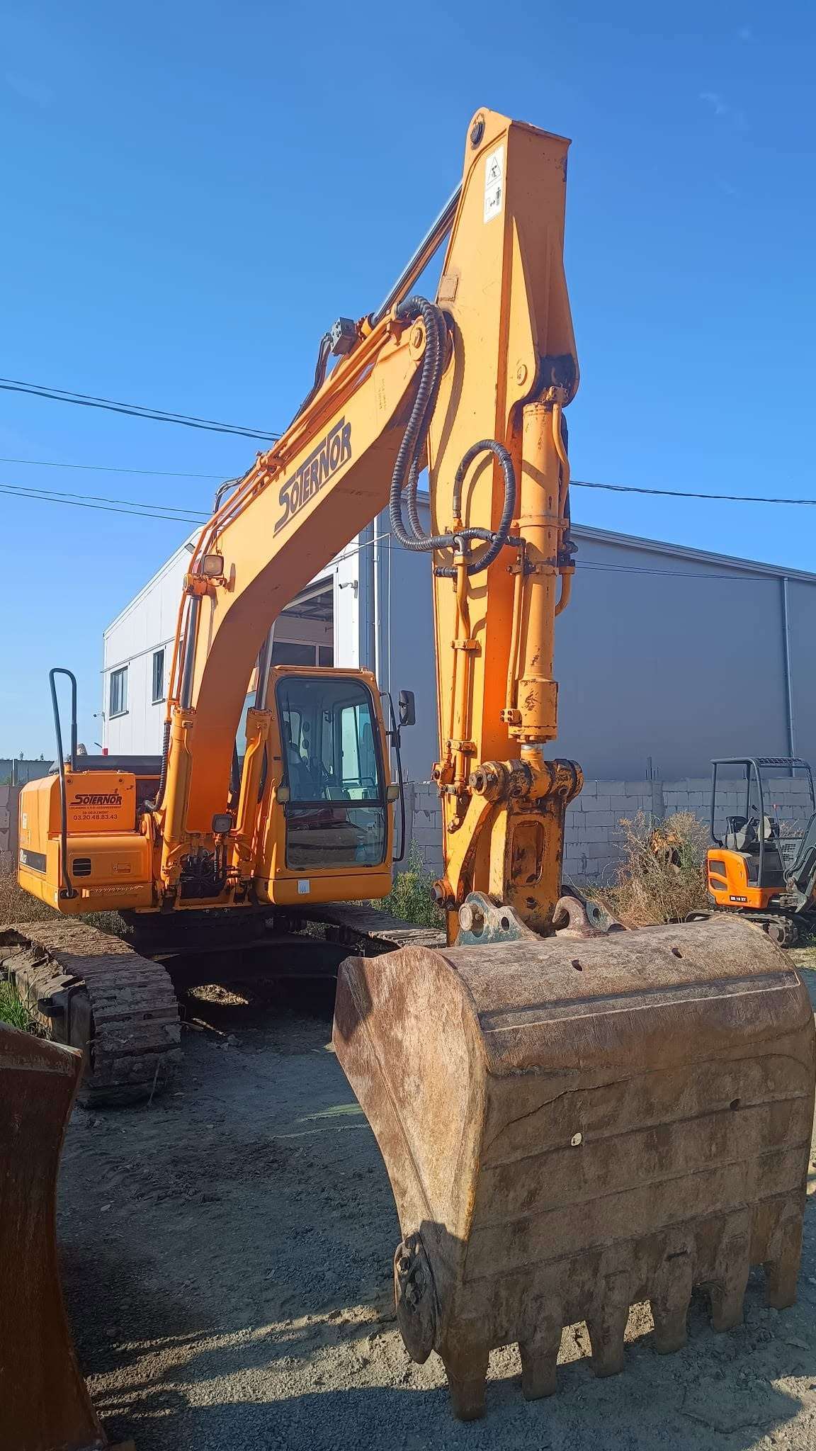 Excavator pe șenile cu cupa ridicată, pe șantier