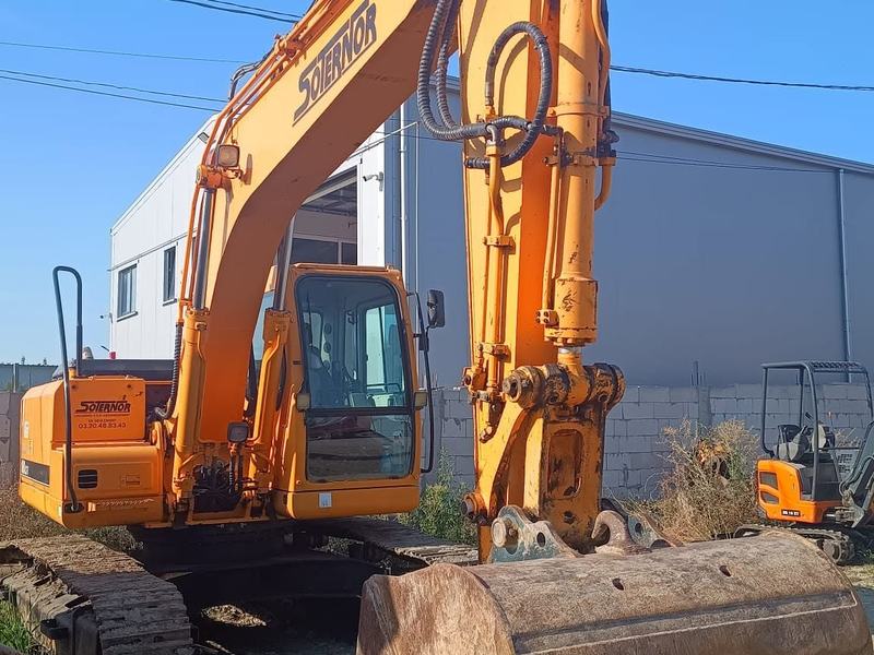Excavator pe șenile cu cupa ridicată, pe șantier