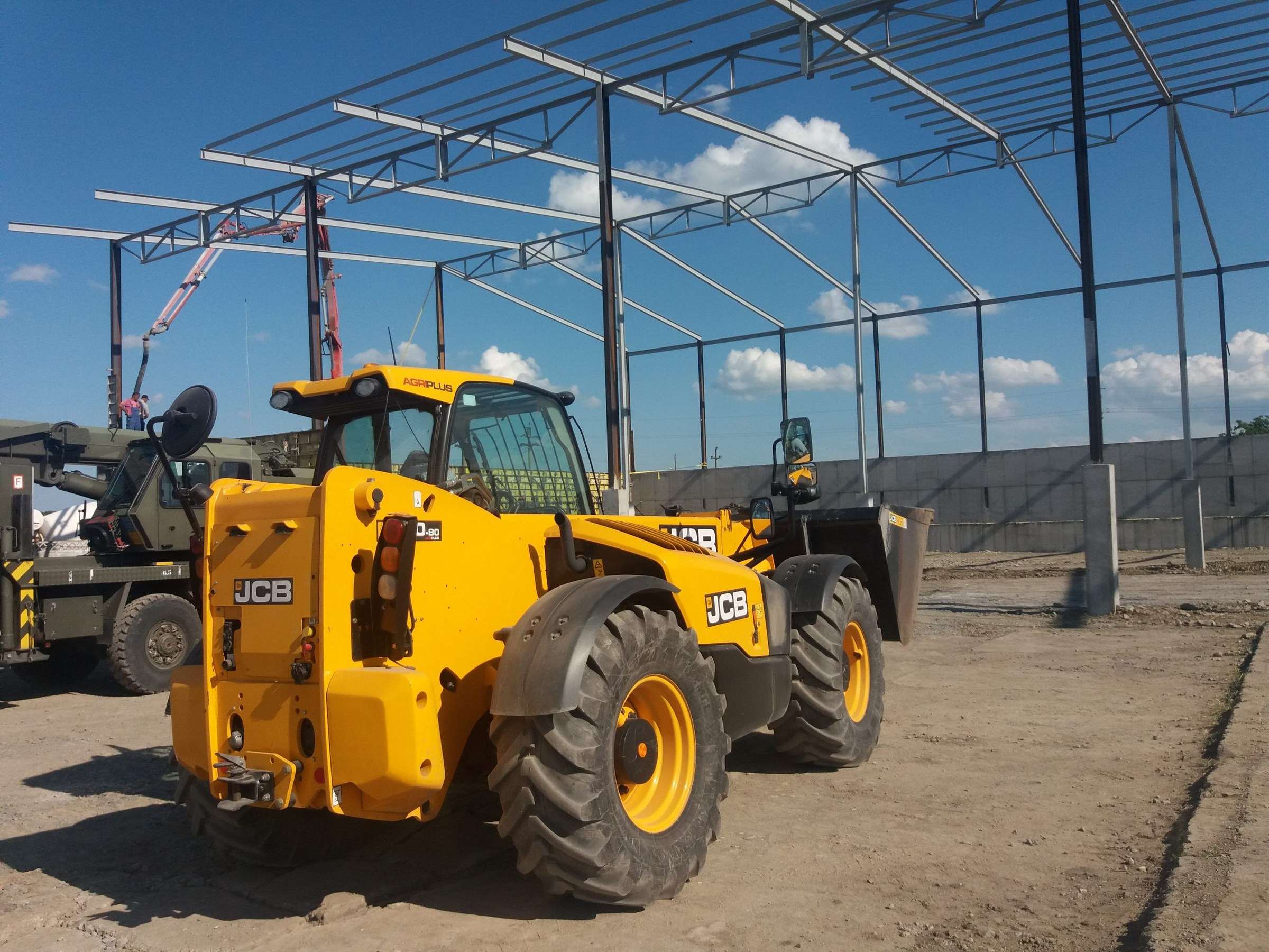 Telehandler JCB galben lângă structura unei hale